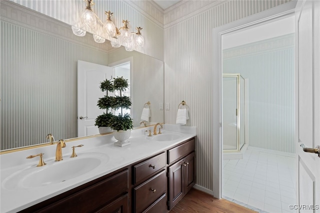 full bath with double vanity, a stall shower, a sink, and wallpapered walls