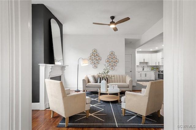 living room with a ceiling fan, a fireplace, baseboards, and wood finished floors