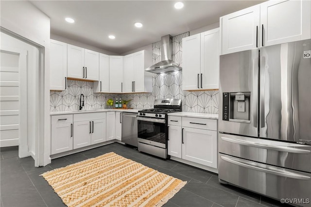 kitchen featuring a sink, stainless steel appliances, wall chimney range hood, light countertops, and dark tile patterned floors