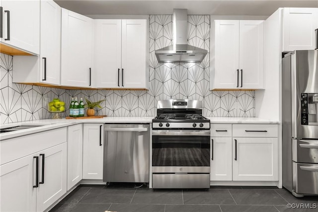 kitchen featuring dark tile patterned floors, wall chimney exhaust hood, appliances with stainless steel finishes, and white cabinets