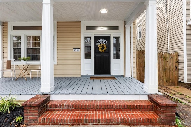 entrance to property with a porch and fence