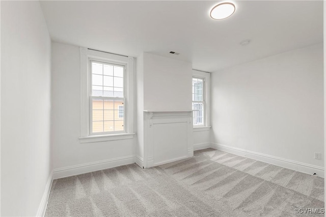 empty room with a wealth of natural light, carpet flooring, and visible vents