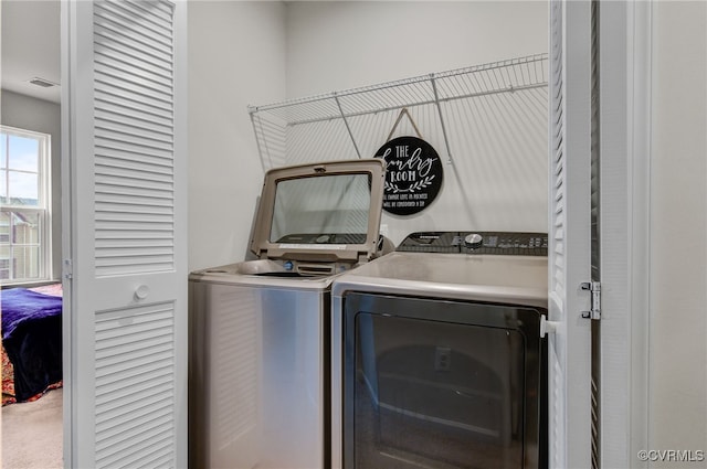 clothes washing area with washing machine and dryer, laundry area, visible vents, and carpet flooring