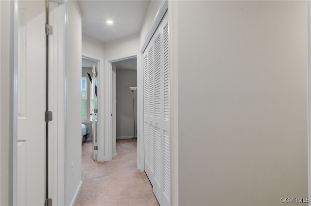 corridor featuring light carpet and baseboards