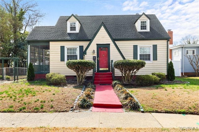 view of front of house with a sunroom, roof with shingles, fence, and a front lawn