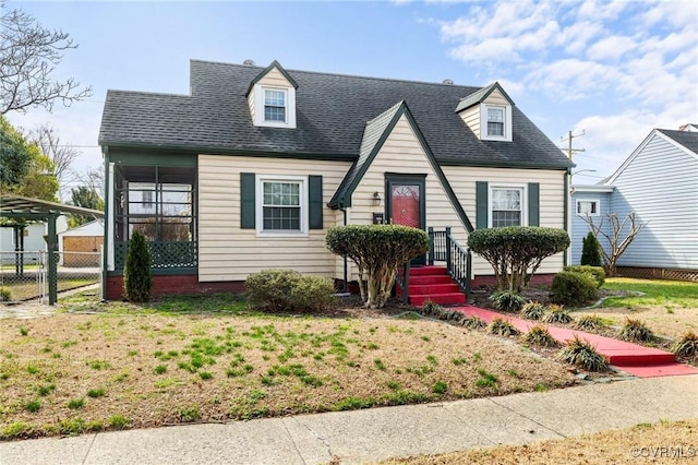 view of front of house featuring a sunroom, fence, a front lawn, and roof with shingles