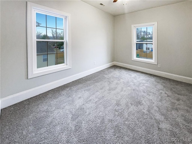 empty room featuring carpet floors, visible vents, baseboards, and a ceiling fan