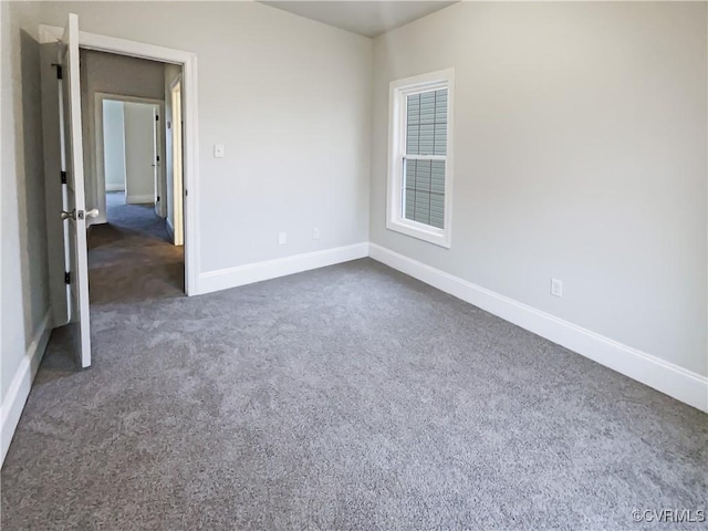 unfurnished room with dark colored carpet and baseboards