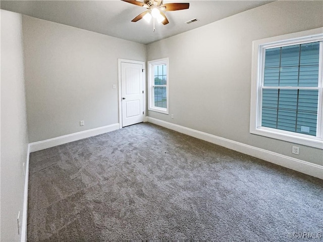 carpeted spare room with a ceiling fan, visible vents, and baseboards