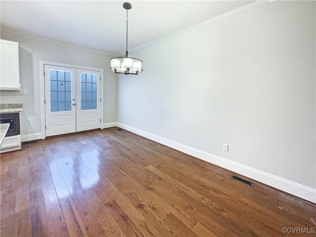 unfurnished dining area featuring ornamental molding, baseboards, visible vents, and dark wood-type flooring