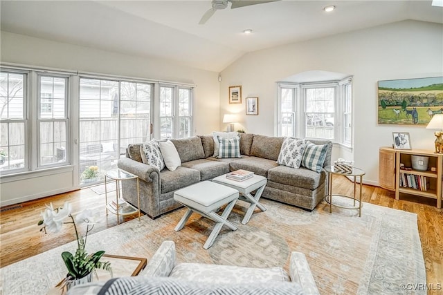 living area with a wealth of natural light, wood finished floors, a ceiling fan, and vaulted ceiling