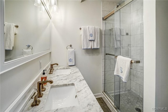 bathroom featuring double vanity, a stall shower, and a sink