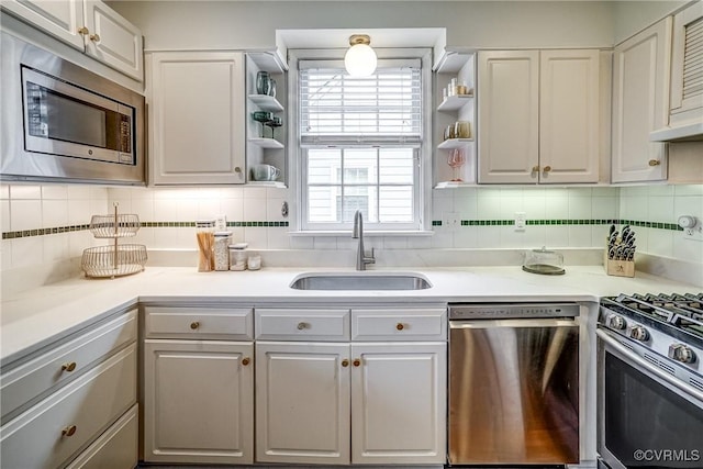 kitchen featuring appliances with stainless steel finishes, light countertops, open shelves, and a sink