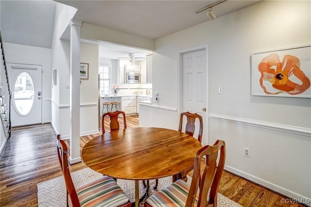 dining room featuring baseboards, a ceiling fan, wood finished floors, and track lighting