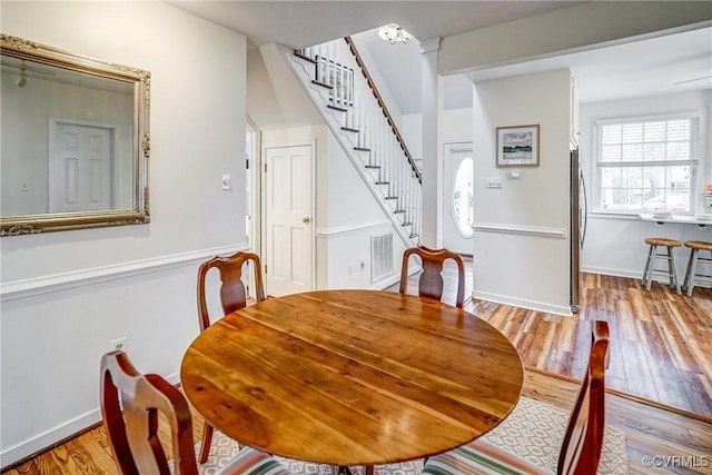 dining area featuring visible vents, baseboards, wood finished floors, and stairway