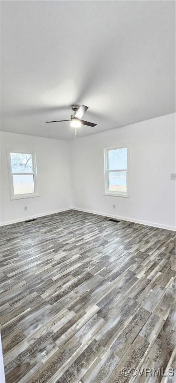 spare room featuring ceiling fan, plenty of natural light, baseboards, and wood finished floors