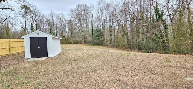 view of yard featuring a storage shed, fence, and an outbuilding