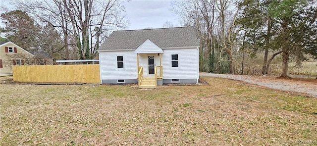 view of front of house with roof with shingles, fence, and a front yard