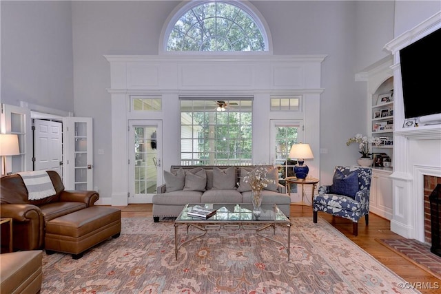 living room with a wealth of natural light, a fireplace, a high ceiling, and wood finished floors