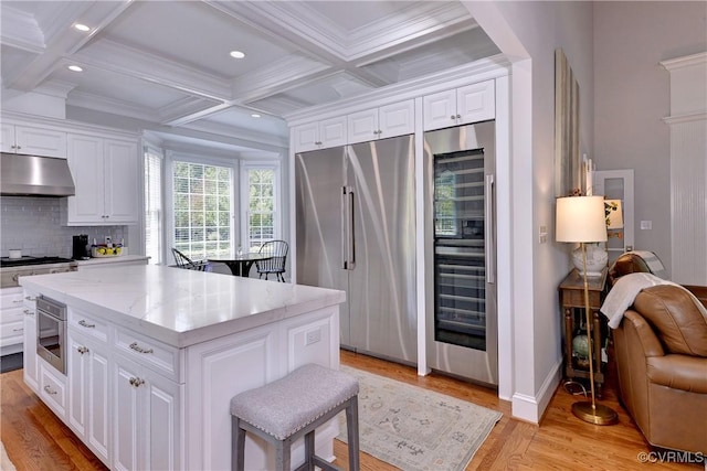 kitchen with stainless steel appliances, decorative backsplash, coffered ceiling, beamed ceiling, and under cabinet range hood