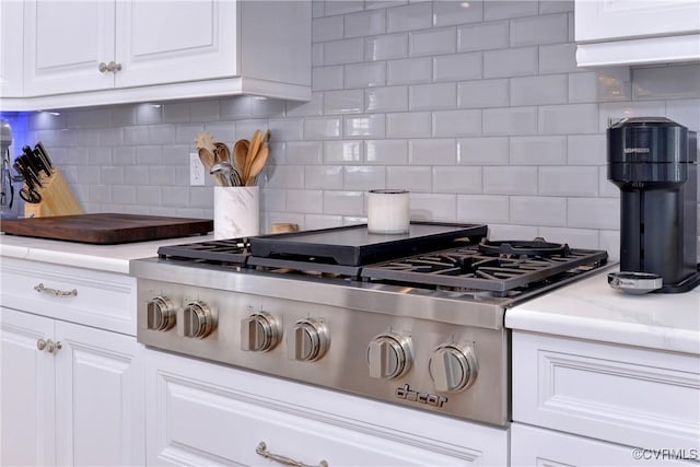 kitchen with light stone countertops, white cabinetry, stainless steel gas cooktop, and tasteful backsplash