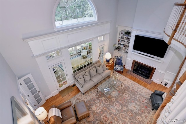 living area featuring a fireplace, a high ceiling, and wood finished floors