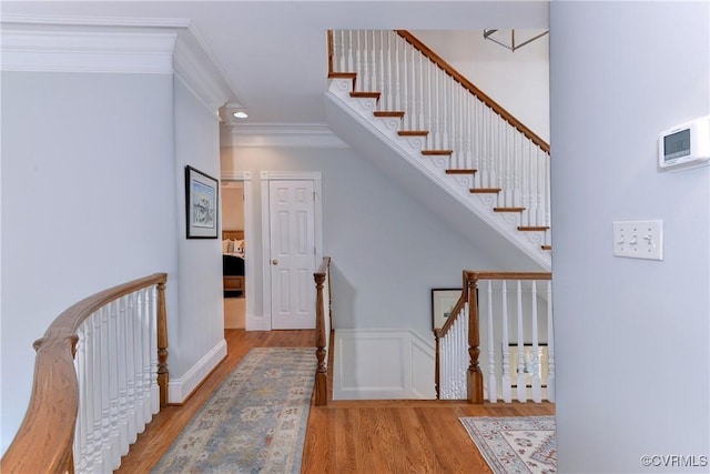 stairs featuring ornamental molding and wood finished floors