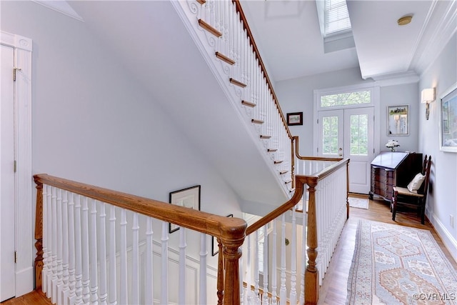 stairway featuring baseboards, ornamental molding, wood finished floors, and french doors