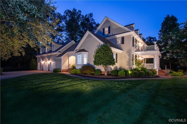 view of front facade with a balcony, driveway, an attached garage, and a front yard