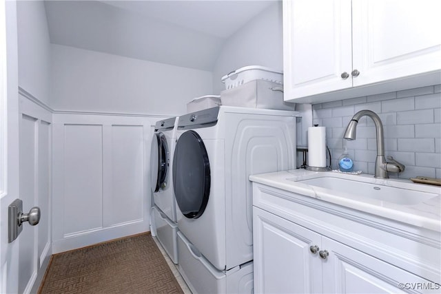 laundry room with washer and clothes dryer, wainscoting, a sink, and cabinet space