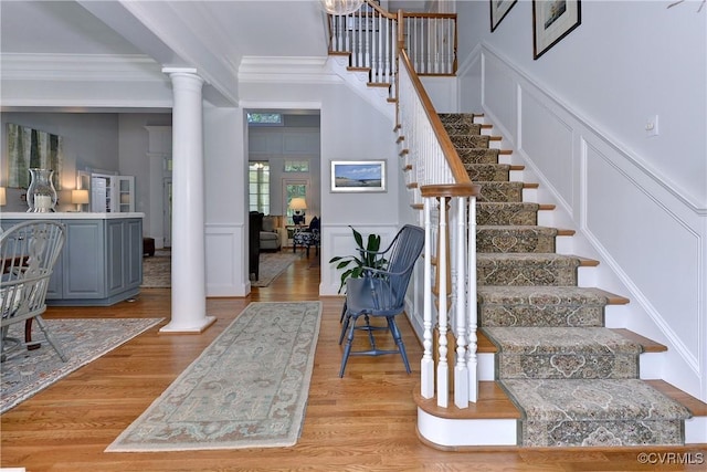 interior space with ornamental molding, decorative columns, and a decorative wall