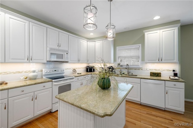 kitchen with tasteful backsplash, light wood-style floors, white cabinets, a sink, and white appliances