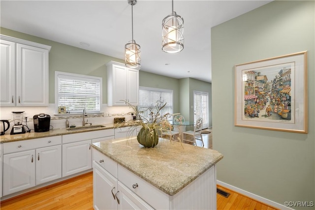 kitchen featuring light wood-style floors, a sink, a wealth of natural light, and a center island