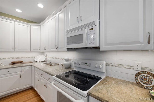 kitchen featuring white appliances, white cabinets, light wood-style flooring, and decorative backsplash