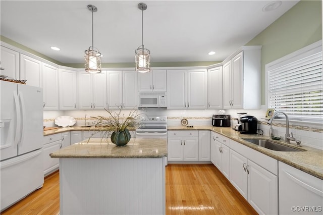 kitchen with white appliances, a sink, light wood-style floors, and white cabinets