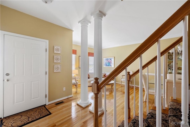 entryway with visible vents, baseboards, light wood-style floors, stairway, and ornate columns