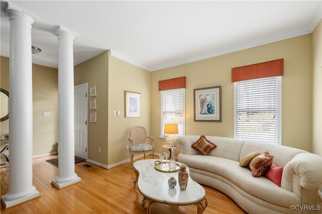 living room with ornate columns, light wood-style flooring, baseboards, and crown molding