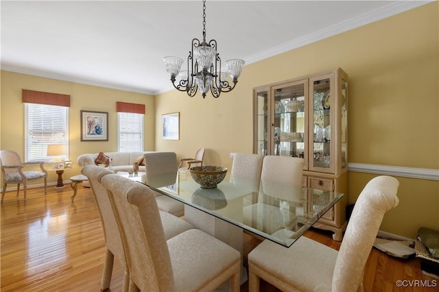 dining room featuring a notable chandelier, crown molding, baseboards, and wood finished floors