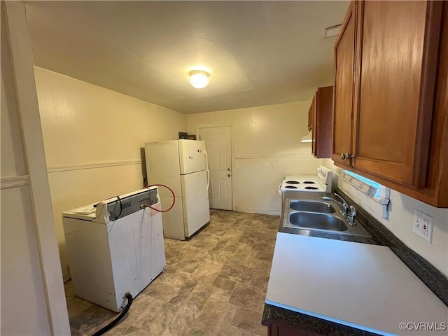 kitchen with white appliances, stone finish flooring, brown cabinets, and a sink