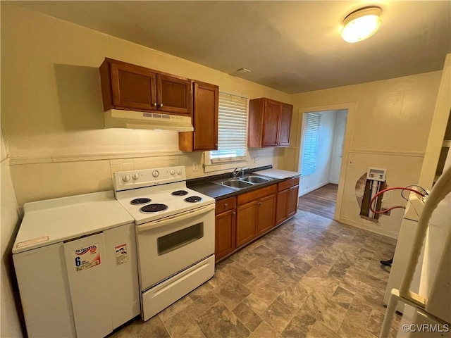 kitchen featuring white electric stove, under cabinet range hood, a sink, fridge, and brown cabinetry