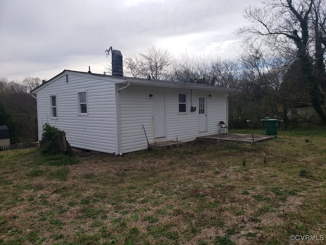 back of house with a patio area, a chimney, and a yard