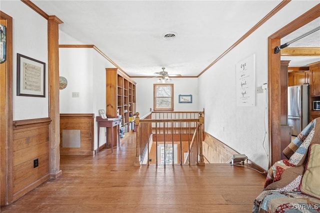 dining space with a wainscoted wall, wood walls, wood finished floors, and visible vents