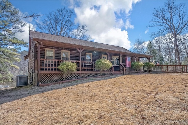 view of front of house featuring covered porch, central AC unit, and a front yard