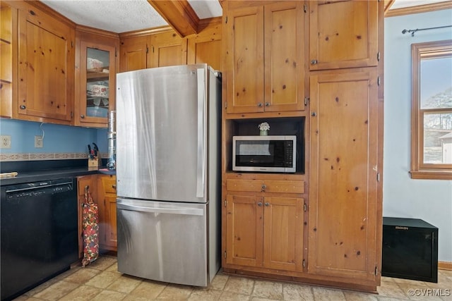 kitchen featuring dark countertops, appliances with stainless steel finishes, brown cabinets, and glass insert cabinets