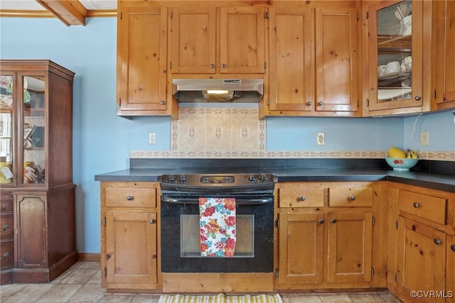 kitchen with dark countertops, under cabinet range hood, black range with electric cooktop, and brown cabinets