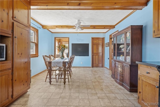 dining area with a ceiling fan, crown molding, beamed ceiling, and baseboards