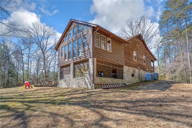 view of side of property featuring stone siding, log veneer siding, a yard, and central AC