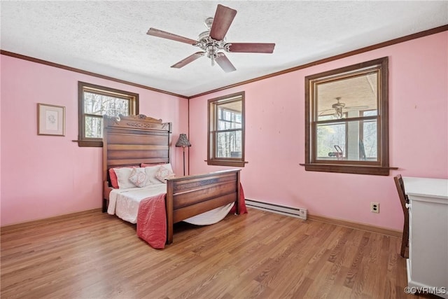 bedroom featuring a textured ceiling, a baseboard heating unit, light wood-style floors, multiple windows, and crown molding