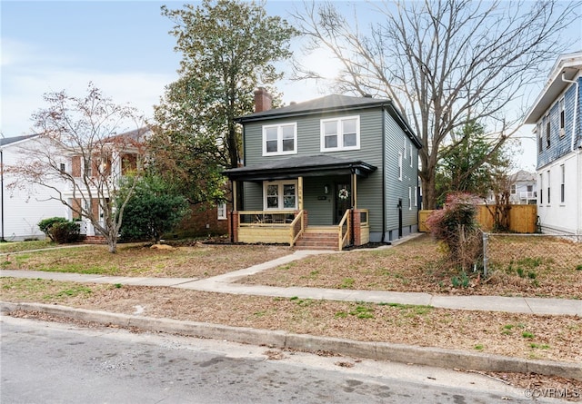 view of front of house featuring a chimney, fence, and a porch