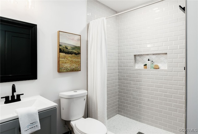 full bathroom with toilet, a tile shower, and vanity